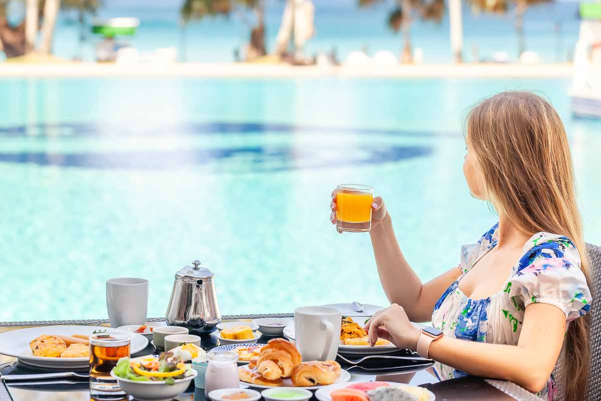 hotel guest in dress eating breakfast by the pool